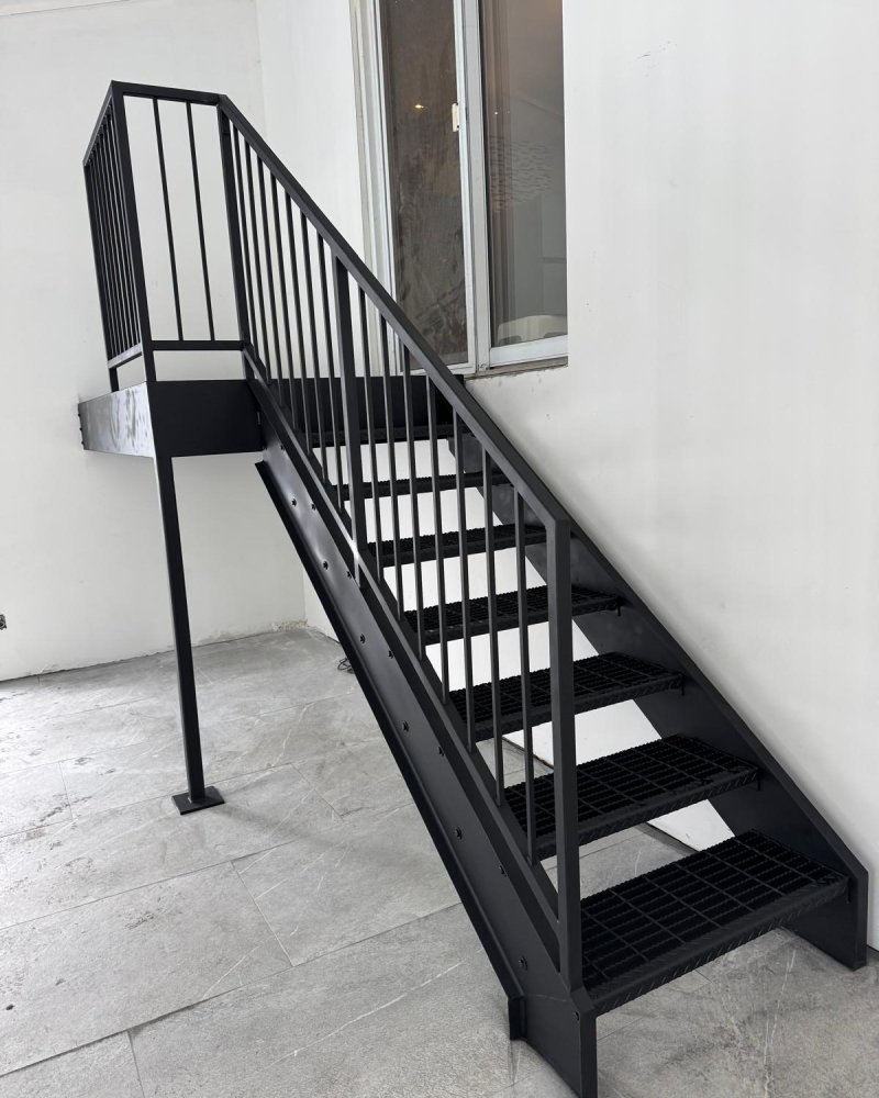 Custom residential steel stair installed in a Toronto home — open-tread design with tube guard and wood handrail