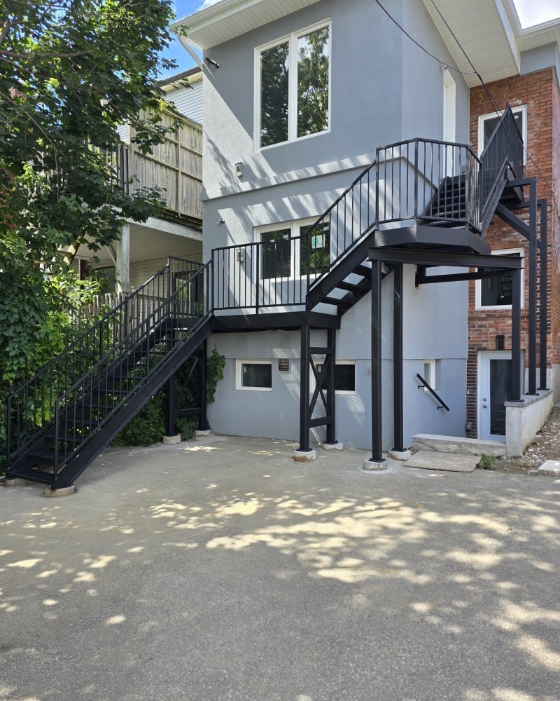 Galvanized exterior roof-access stair on an Ontario commercial building, leading to a rooftop mechanical platform
