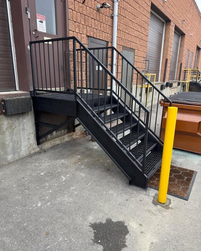 Galvanized exterior fire-escape stair installed against an Ontario warehouse wall